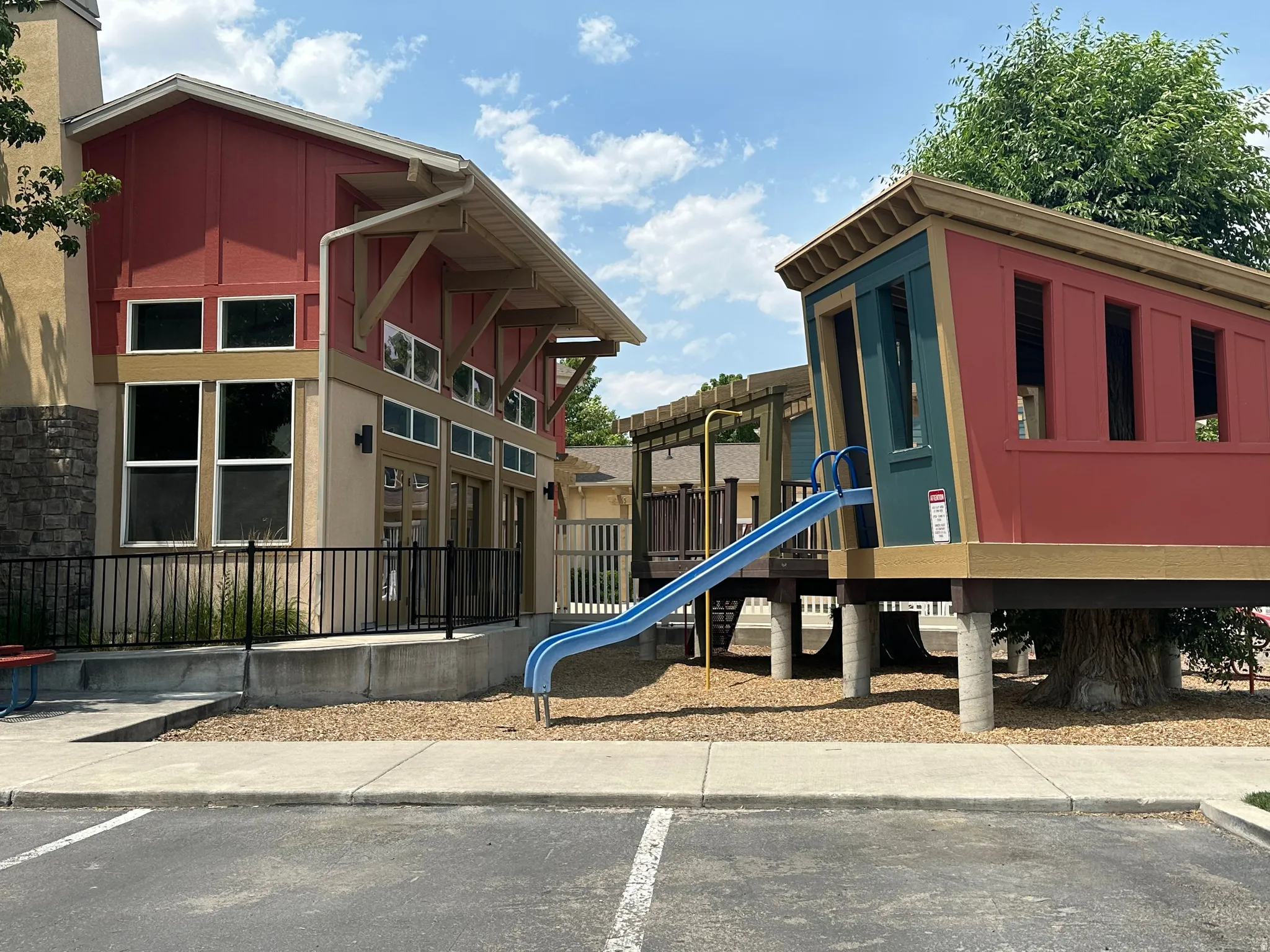 Community recreation area featuring a modern clubhouse building with a red facade and stone accents