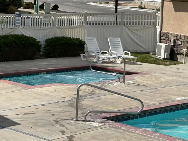 Outdoor spa with bubbling water, accompanied by a swimming pool featuring stainless steel handrails