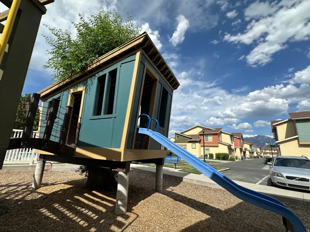 Elevated play structure featuring a blue slide and wood-paneled siding