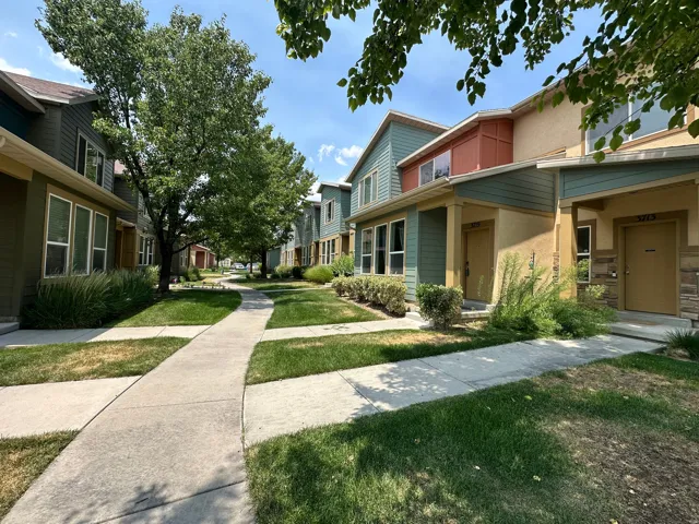 Row of multi-story residences featuring varied siding materials including board and batten, stucco, and stone veneer accents