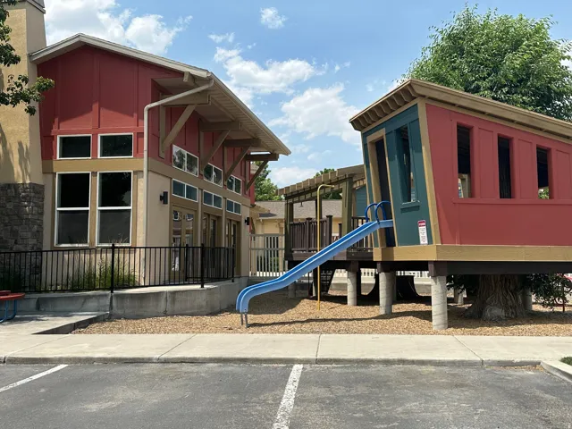 Community recreation area featuring a modern clubhouse building with a red facade and stone accents