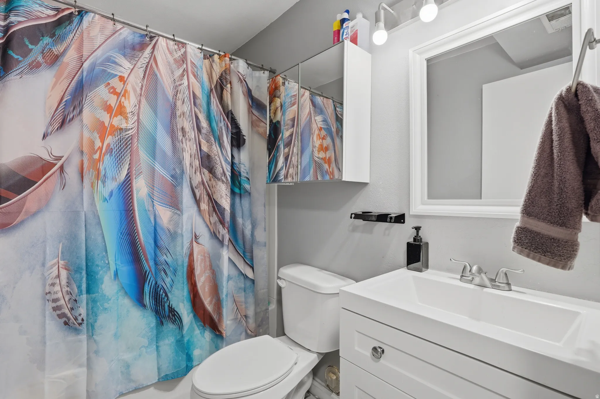 Contemporary bathroom featuring a white vanity with integrated sink, chrome faucet, and framed mirror