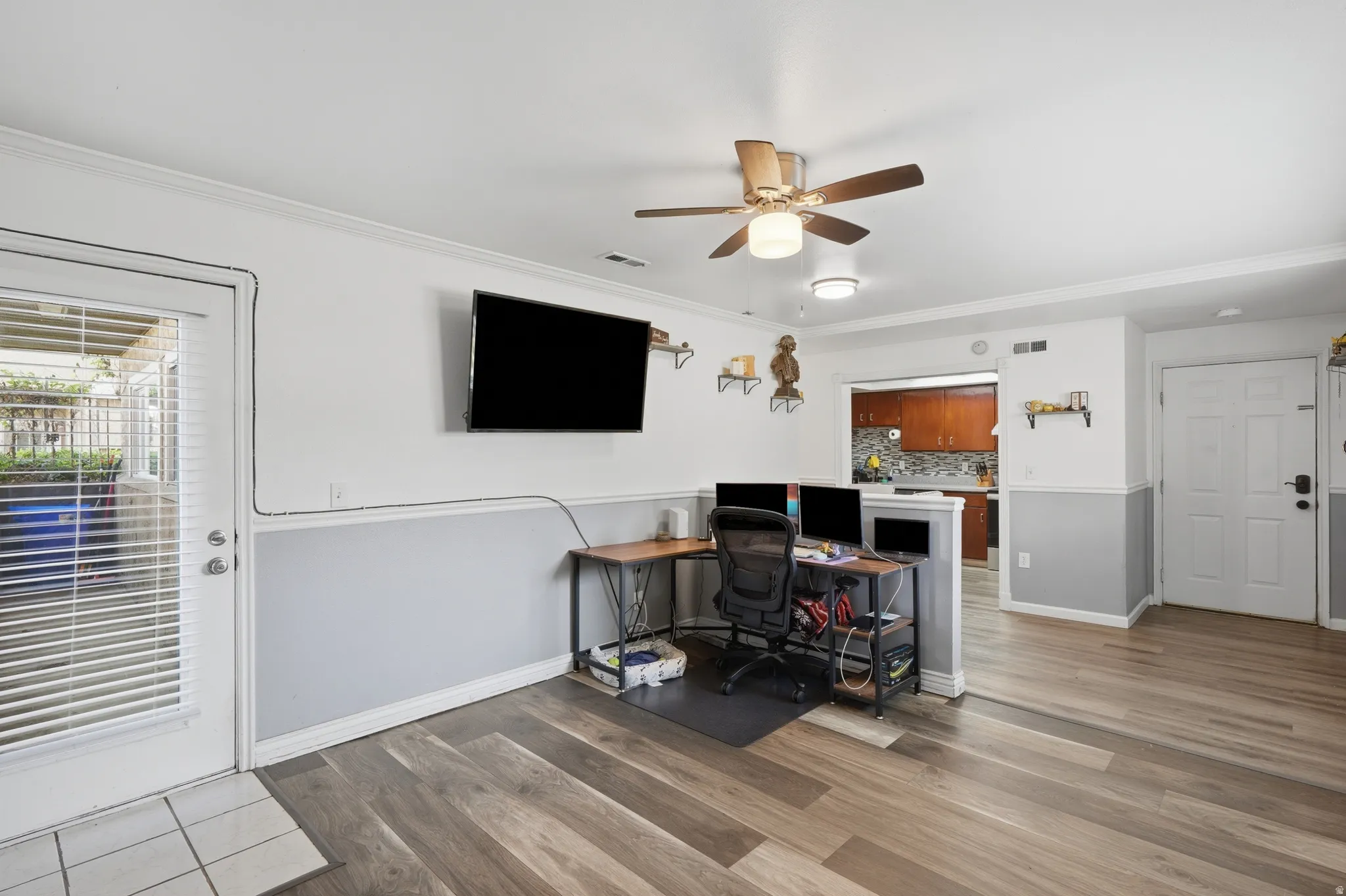 Spacious room featuring wood-finish flooring, two-tone wall paneling, and crown molding