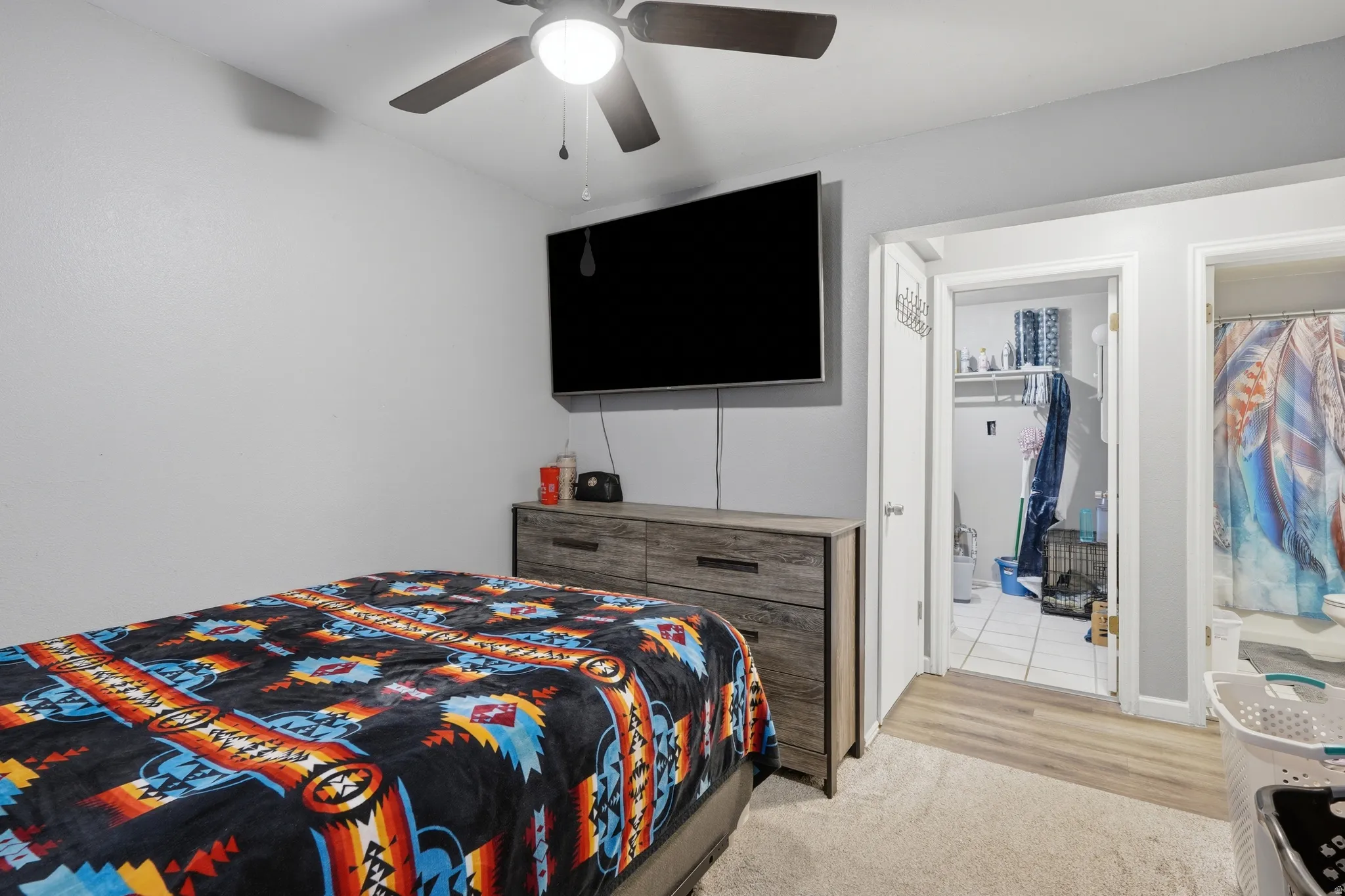 Bedroom featuring a ceiling fan with integrated lighting, light gray walls, and wood-finish flooring
