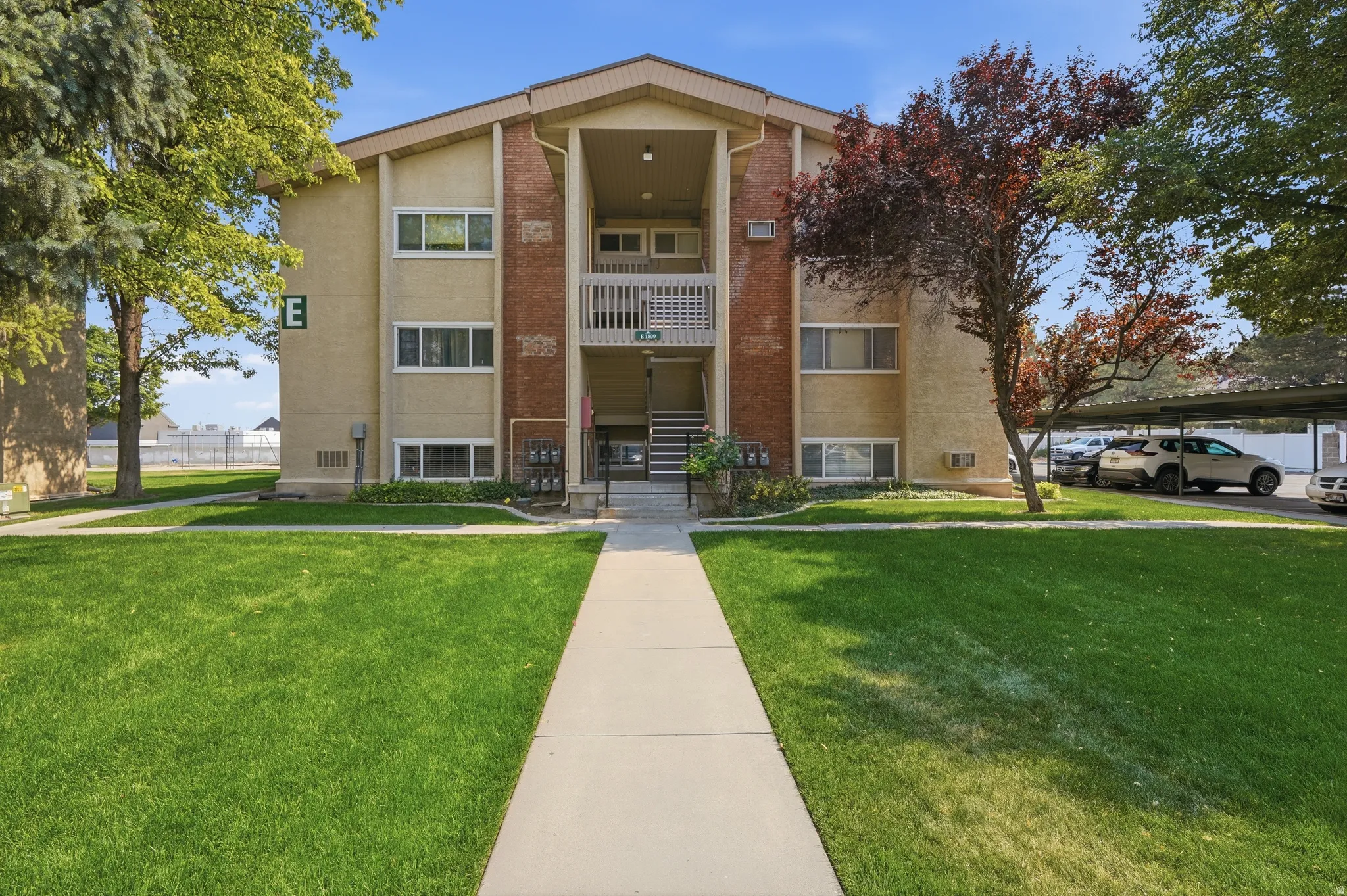 Multi-level residential building featuring a covered entryway, private balconies, and brick accents