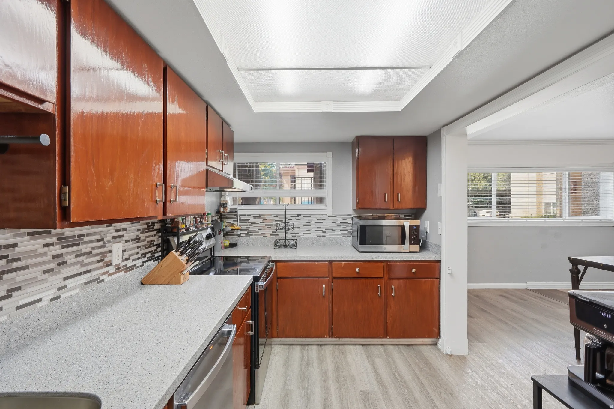 Kitchen featuring wood-finish cabinetry, light-toned countertops, and a mosaic tile backsplash