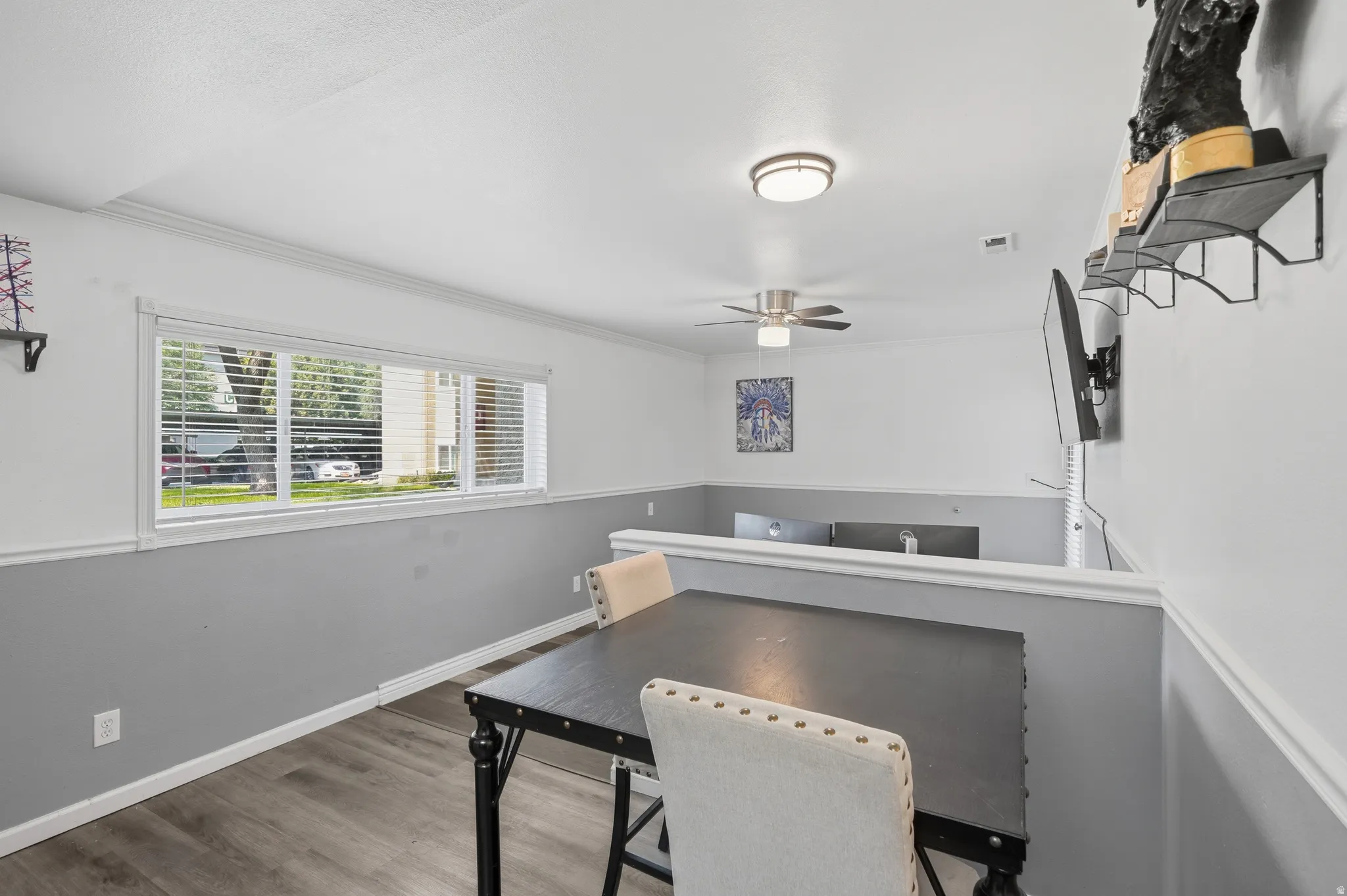 Dining area featuring wood-finish flooring, a contemporary ceiling fan, and a wide window with blinds