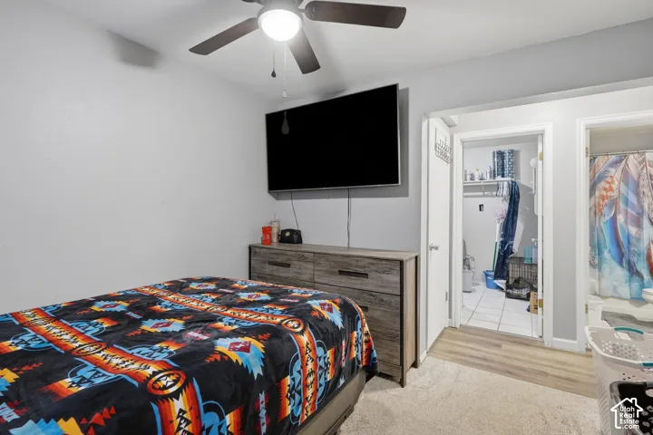 Bedroom featuring a ceiling fan with integrated lighting, light gray walls, and wood-finish flooring