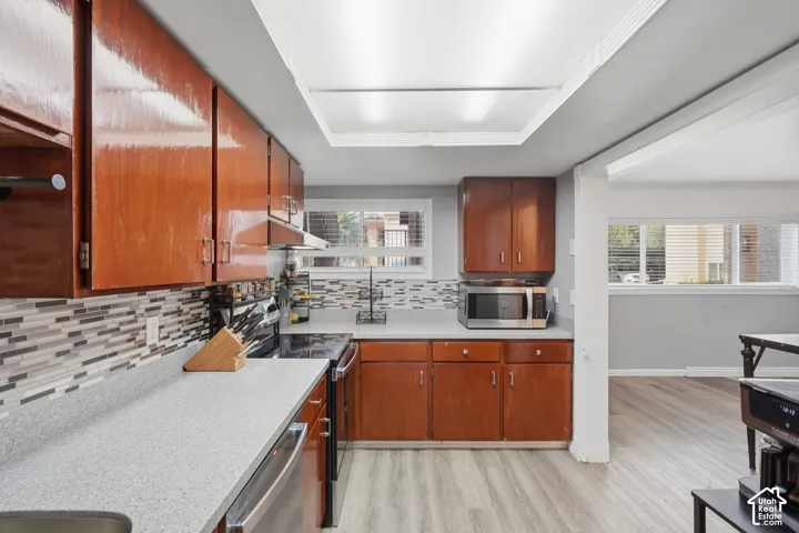Kitchen featuring wood-finish cabinetry, light-toned countertops, and a mosaic tile backsplash