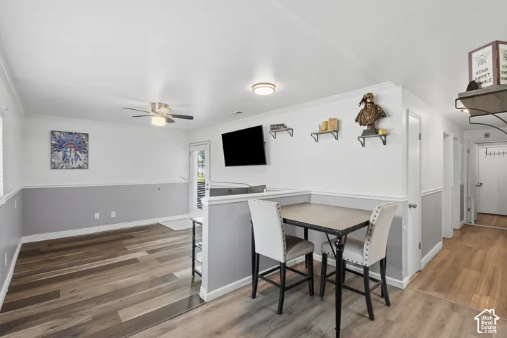 Open-concept living space with wood-finish flooring, white walls, and a grey wainscoting accent