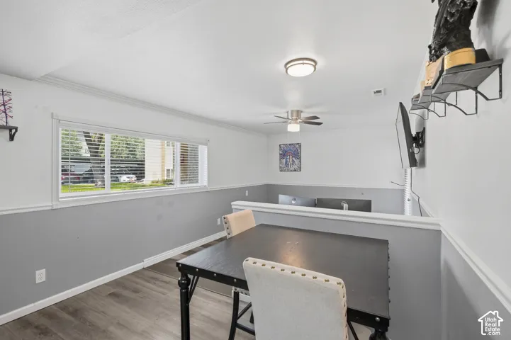 Dining area featuring wood-finish flooring, a contemporary ceiling fan, and a wide window with blinds