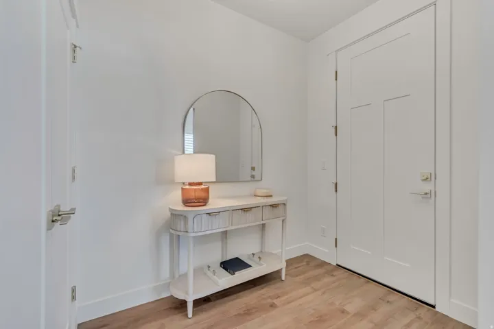 Entryway featuring wood-finish flooring, white trim, and a contemporary arched mirror