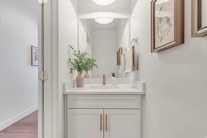 White vanity with brass hardware, undermount sink, and light countertop