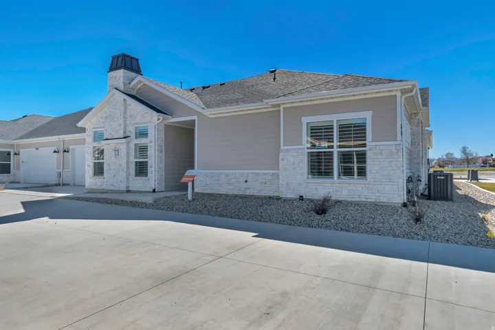 Exterior facade with stone and siding accents, prominent chimney feature, shuttered windows, and a concrete driveway