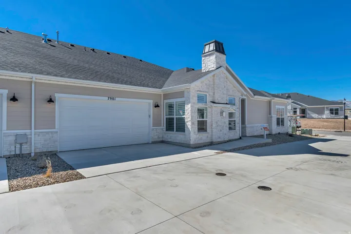 Attached garage with a white panel door, light siding, and stone veneer accents