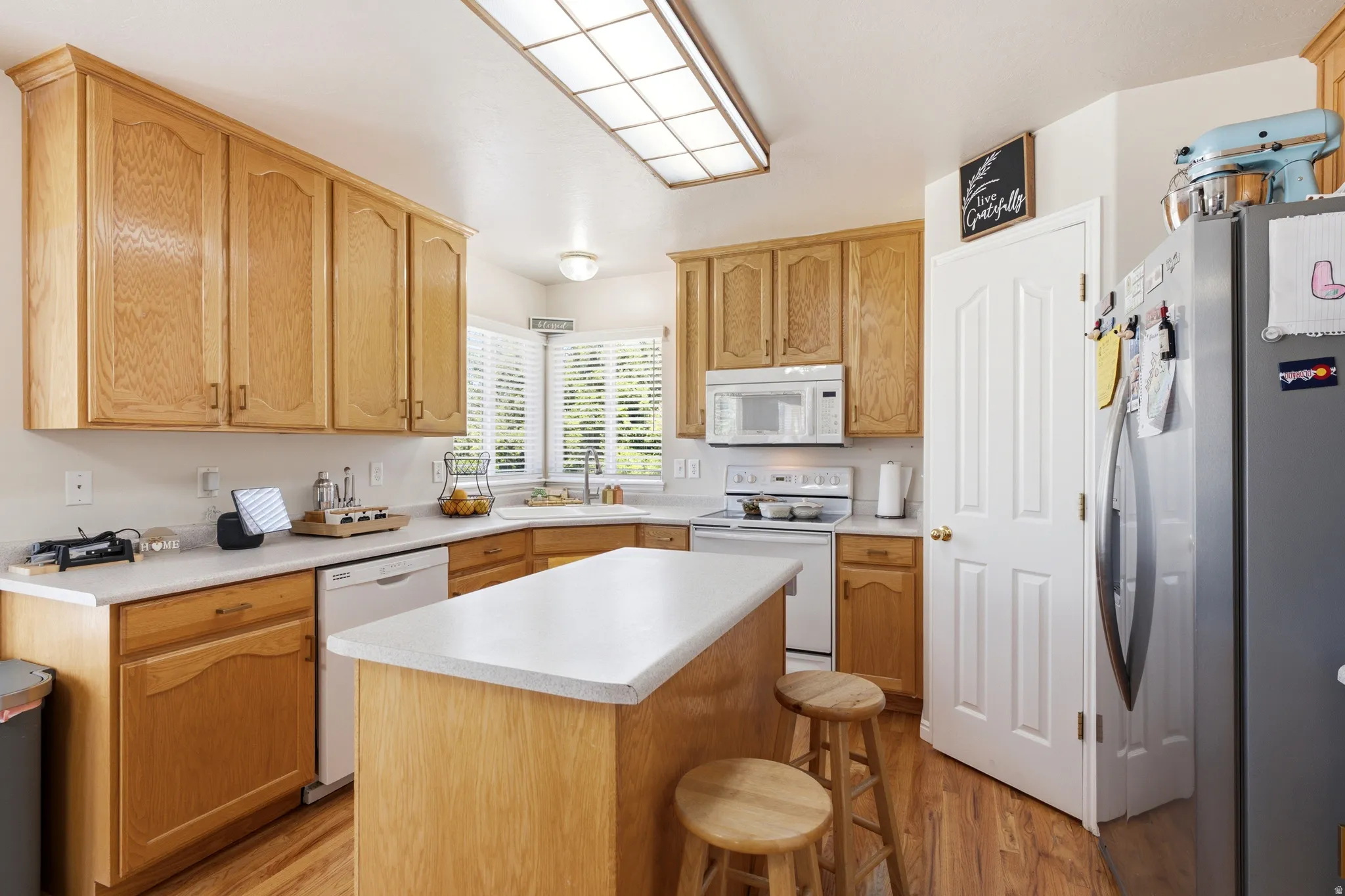 Kitchen featuring wood-finish cabinetry, white countertops, a central island, and wood-finish flooring