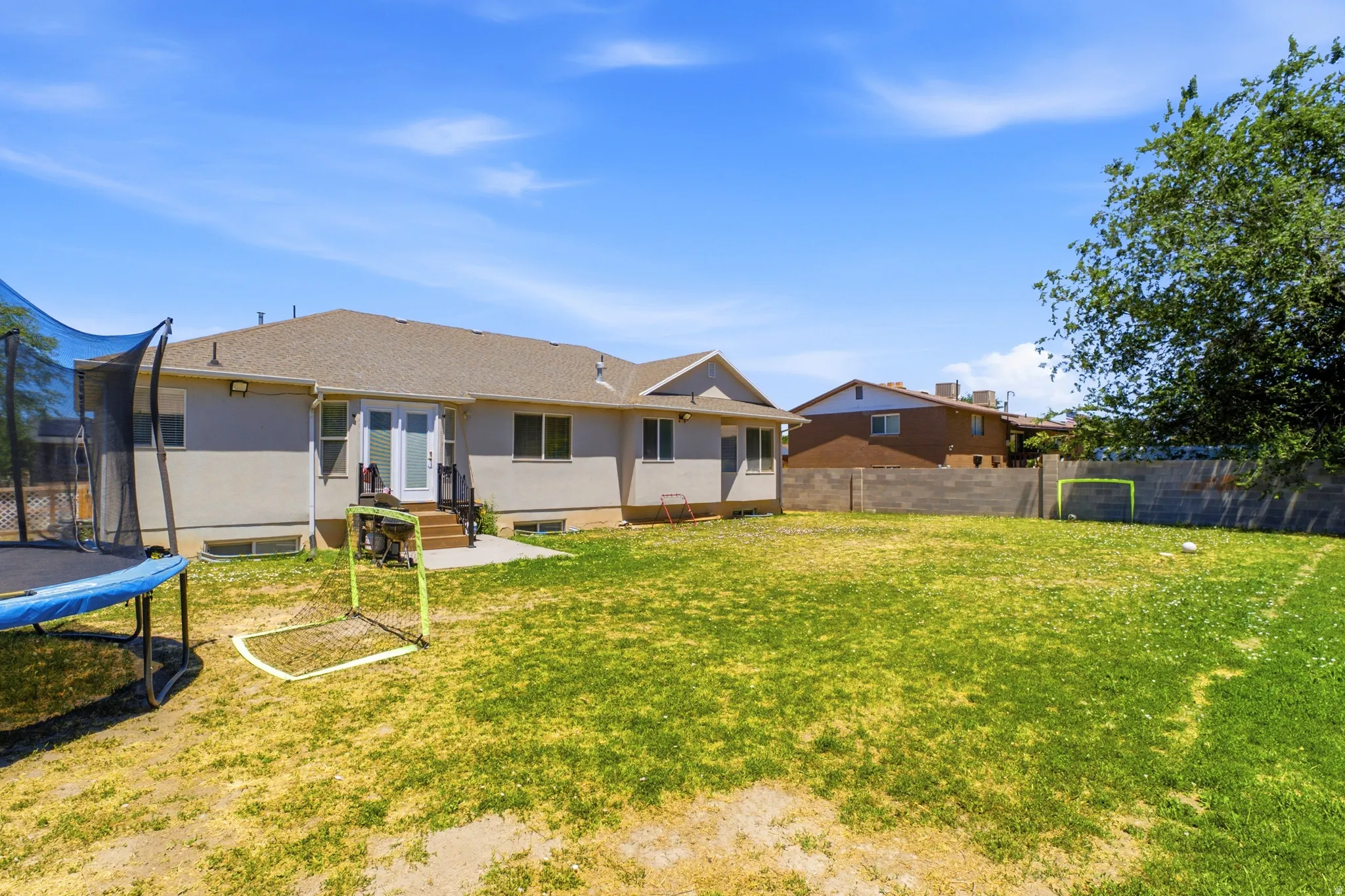 Spacious backyard featuring a stucco exterior, double glass French doors, and a concrete patio