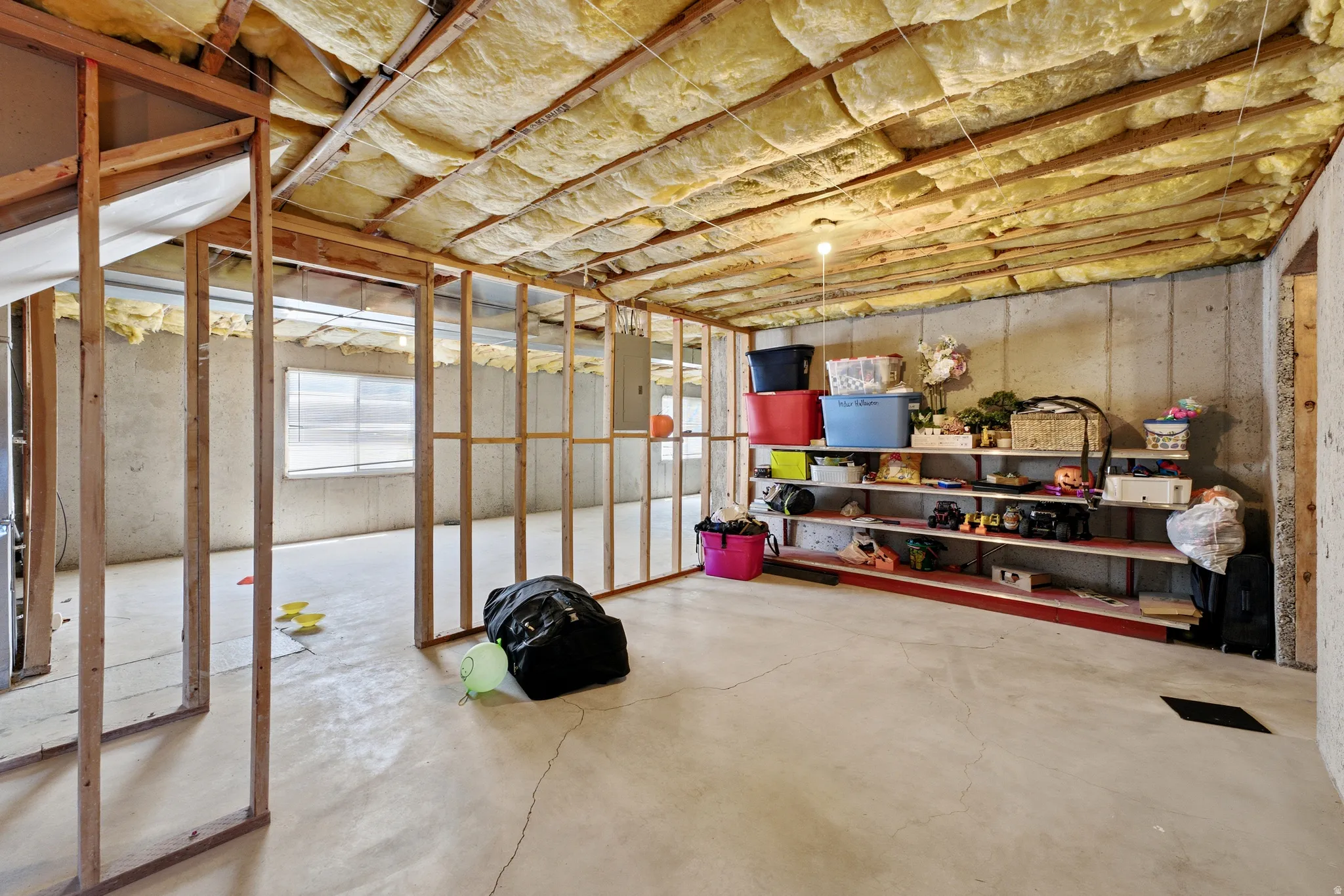 Unfinished basement featuring concrete flooring, exposed wood framing, and a concrete foundation wall