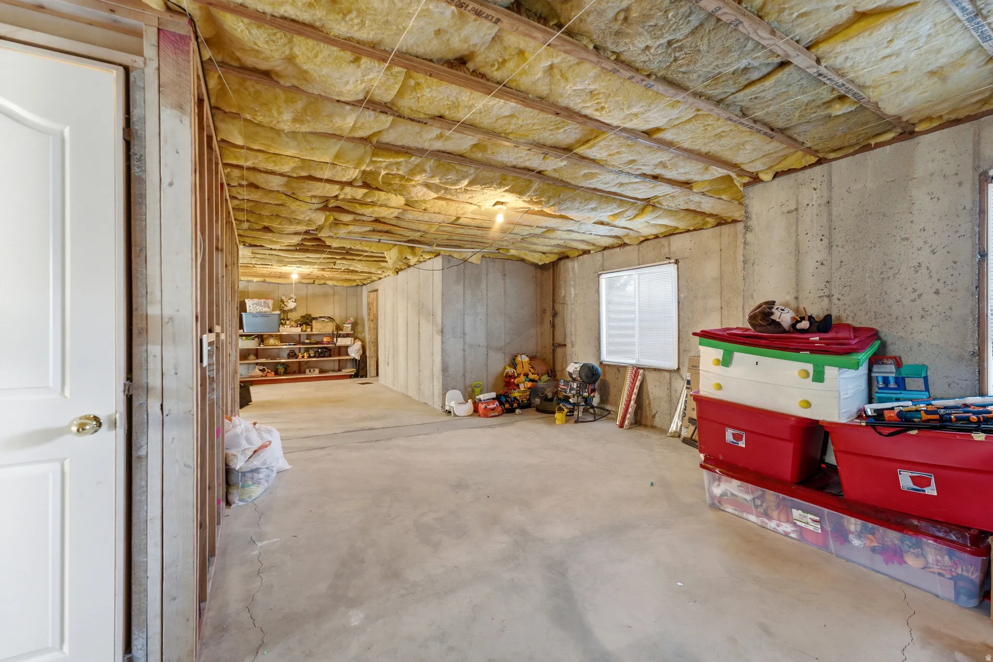 Unfinished basement space featuring concrete flooring, exposed ceiling insulation, and visible framing