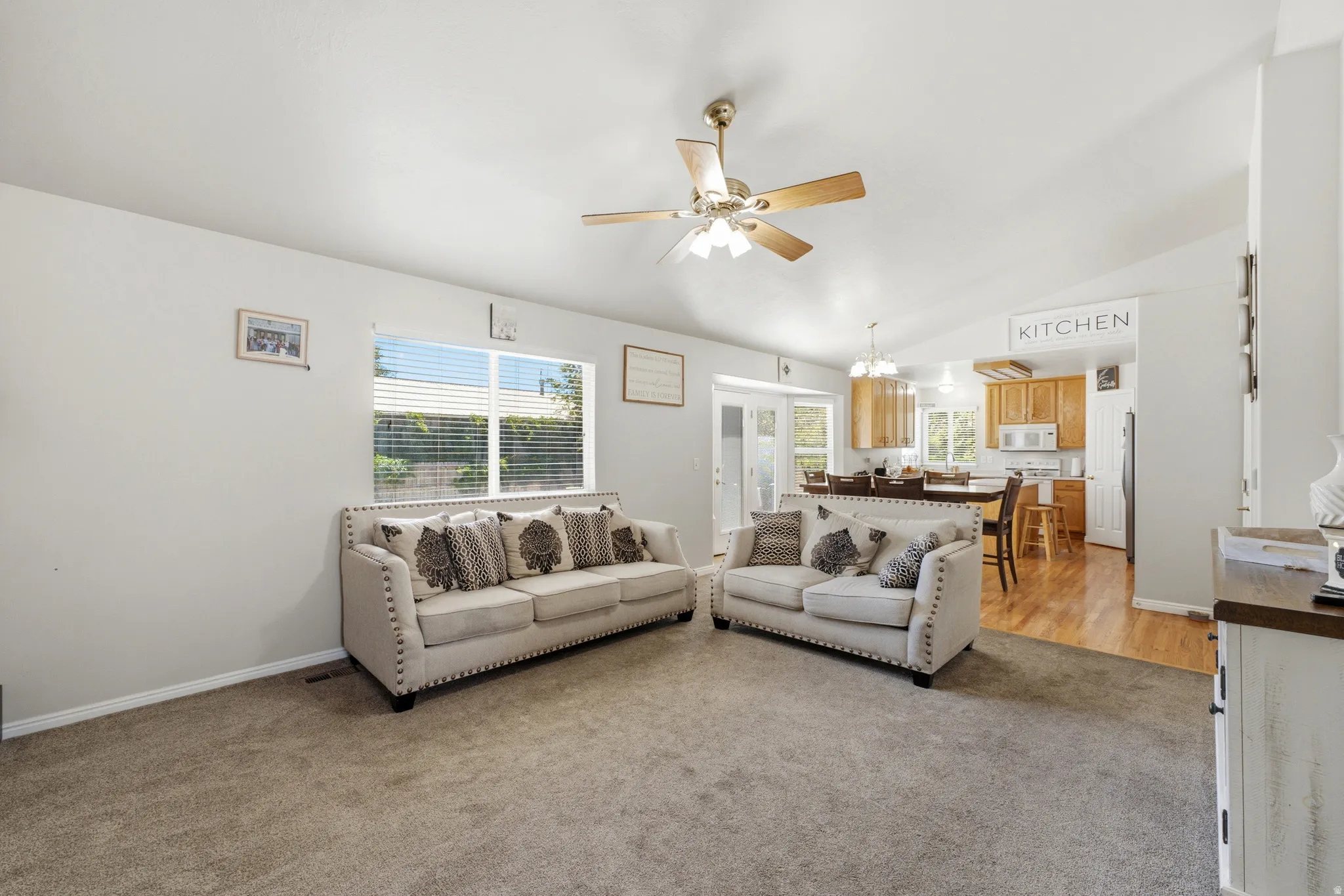 Carpeted living area with a ceiling fan, recessed lighting, and a large window with blinds