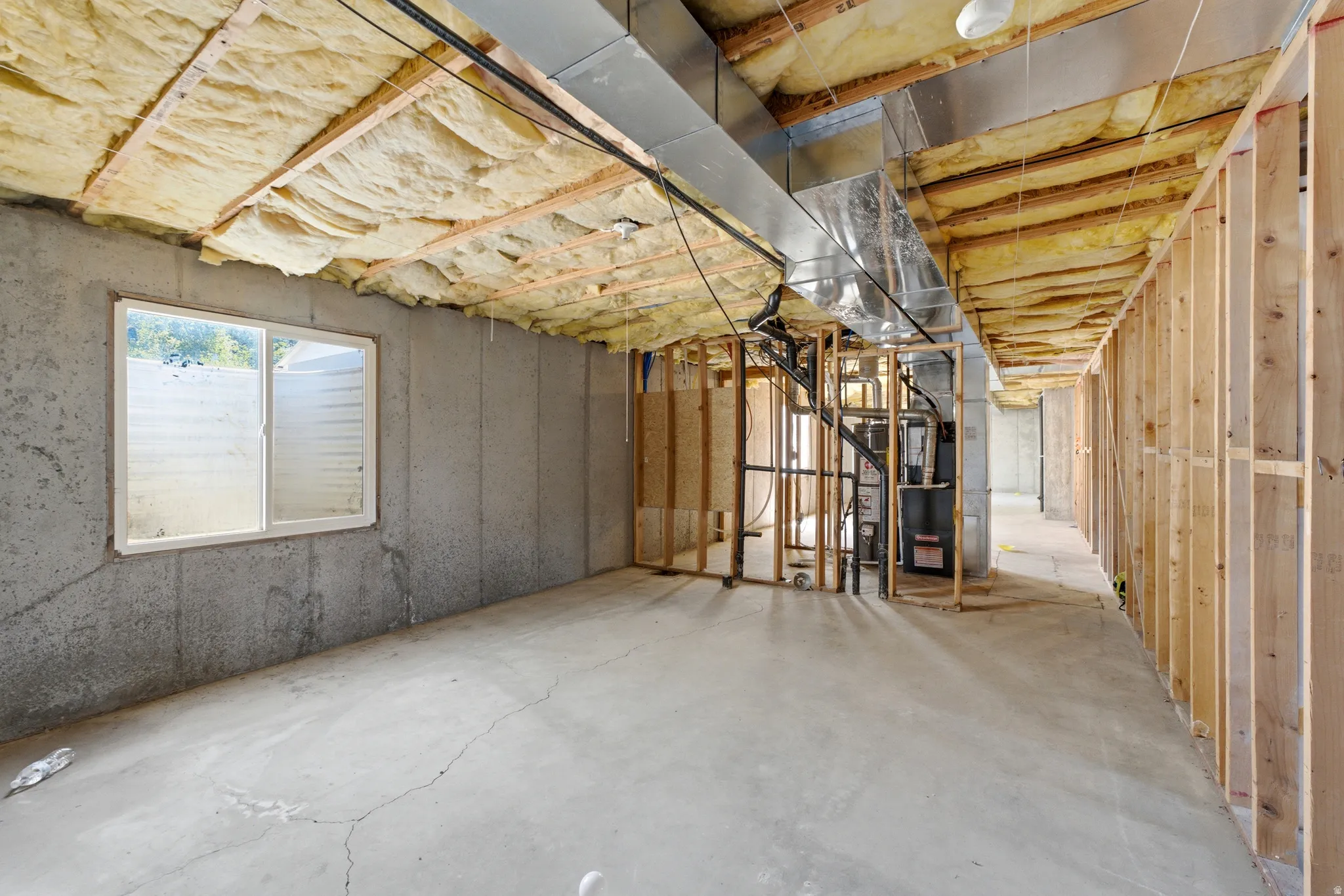Unfinished basement with concrete flooring, exposed ceiling insulation, and a double-hung window