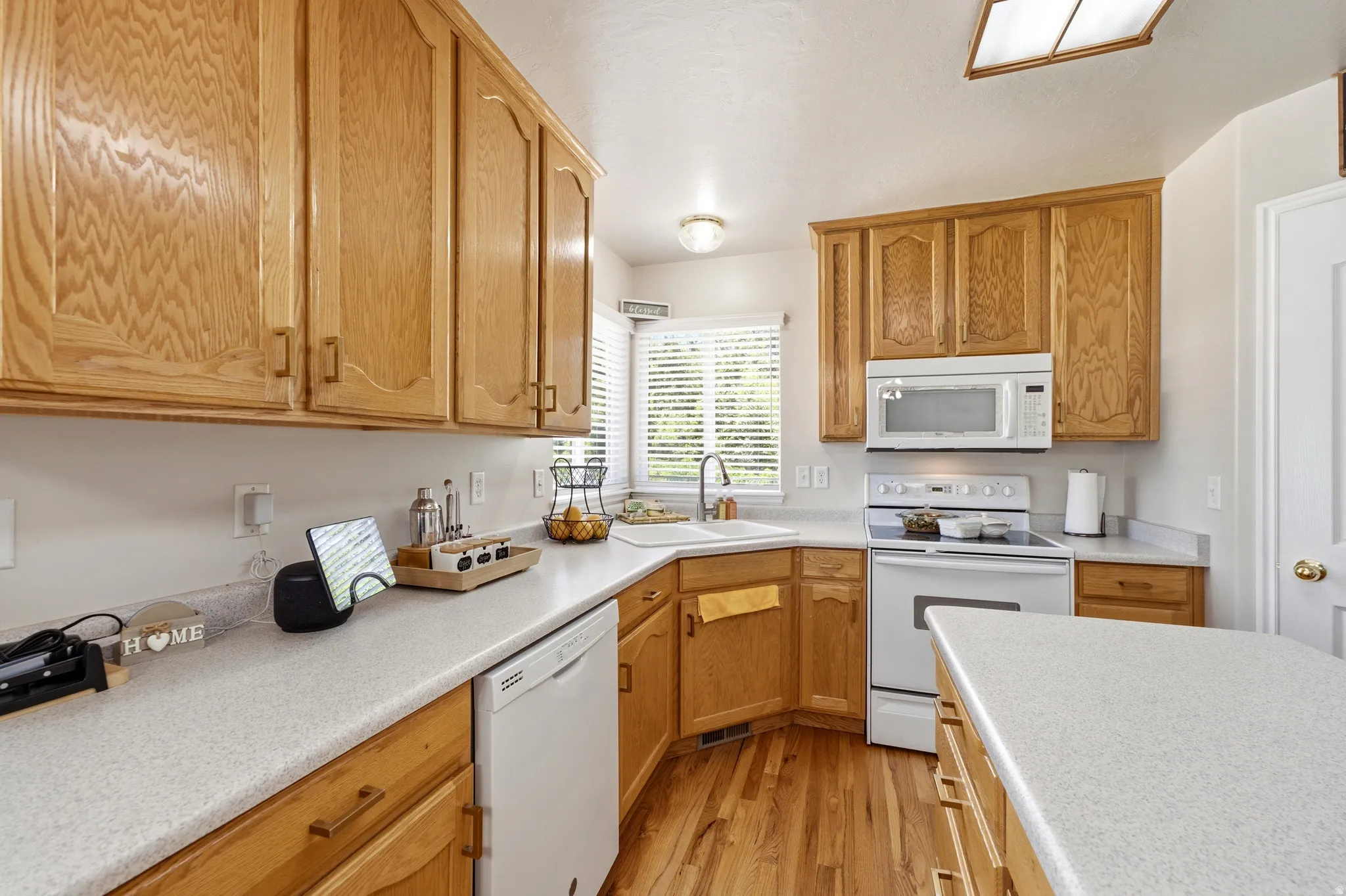 Kitchen featuring wood-finish cabinetry, light-toned countertops, and wood-finish flooring