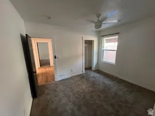 Carpeted room with a ceiling fan and a window