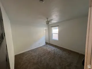 Carpeted room with a single window, a ceiling fan, and white baseboards