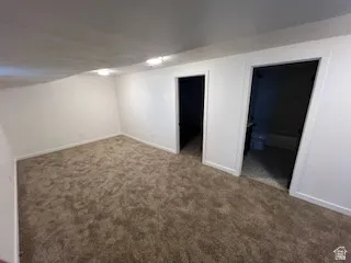 Carpeted room featuring white painted walls and two doorways