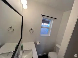 Bathroom featuring a rectangular vanity mirror, white sink basin, wall-mounted light fixture, and a window with a black curtain rod