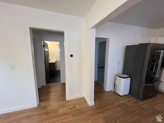 Wood-finish flooring throughout, featuring a stainless steel refrigerator and white walls