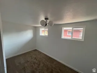 Carpeted room featuring two horizontal sliding windows with white frames, a contemporary three-globe ceiling fixture, and light-toned wall finishes