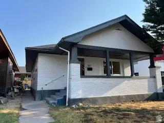 Single-story residence featuring a covered front porch with dark-painted columns, white brick siding, and a dark-toned roof