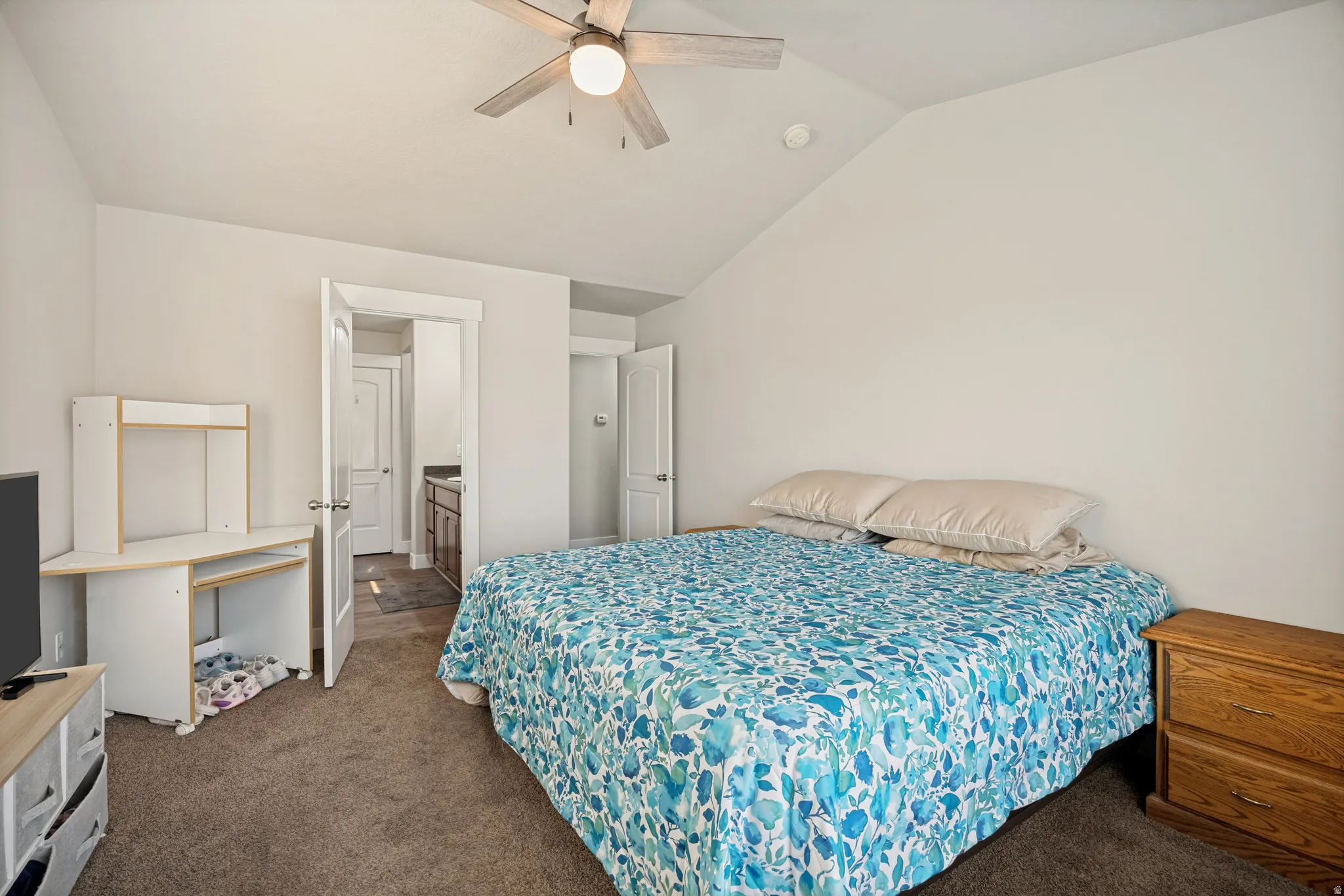 Carpeted bedroom featuring an angled ceiling, ceiling fan with integrated lighting, and white trim