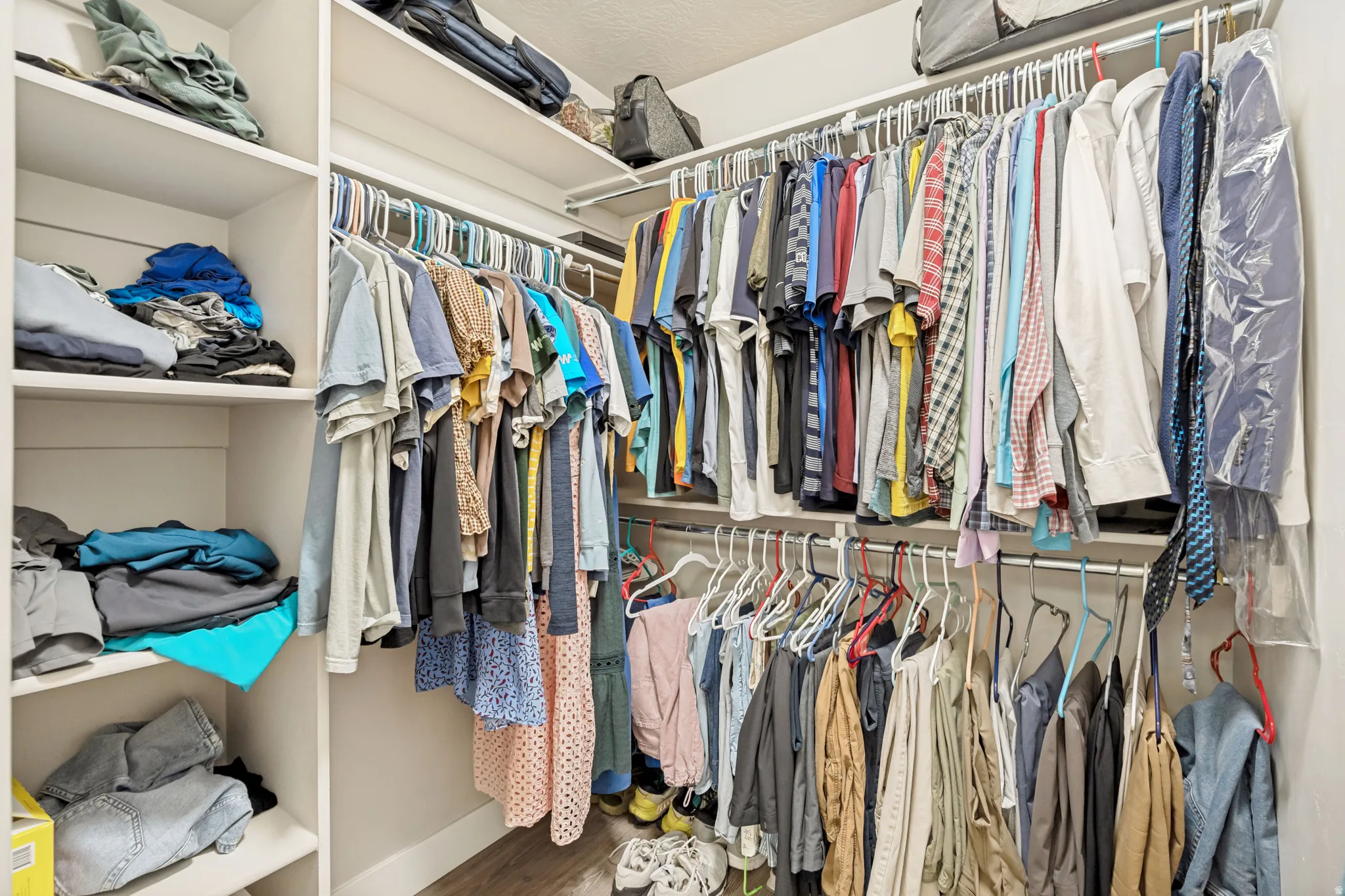 Custom closet system featuring multiple hanging rods, integrated shelving units, and wood-finish flooring