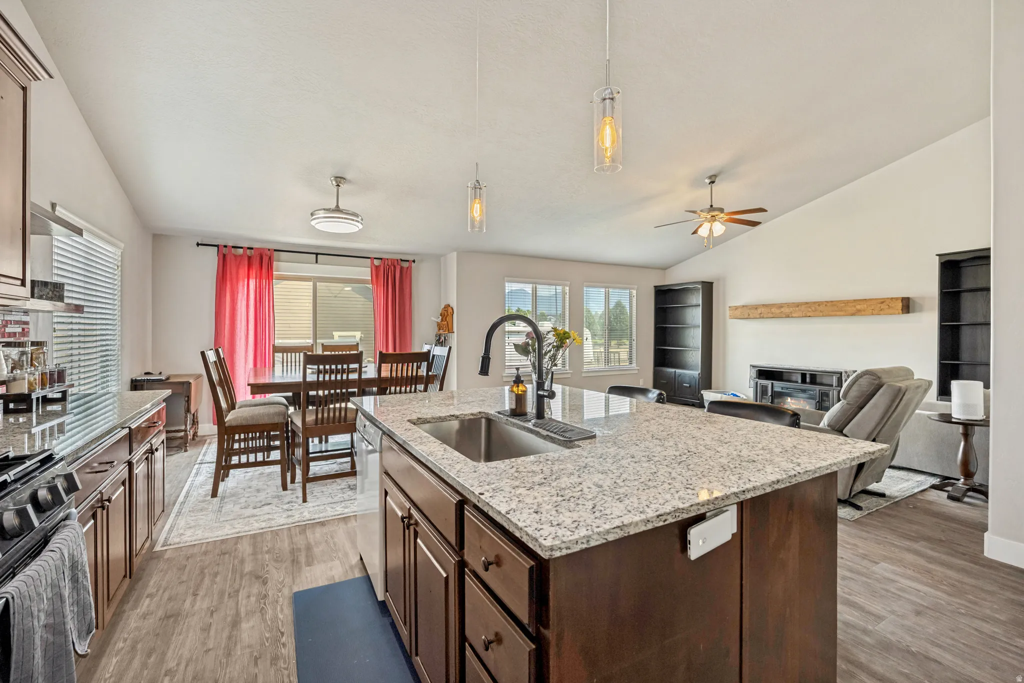 Kitchen island featuring a granite countertop, undermount sink, and dark wood cabinetry