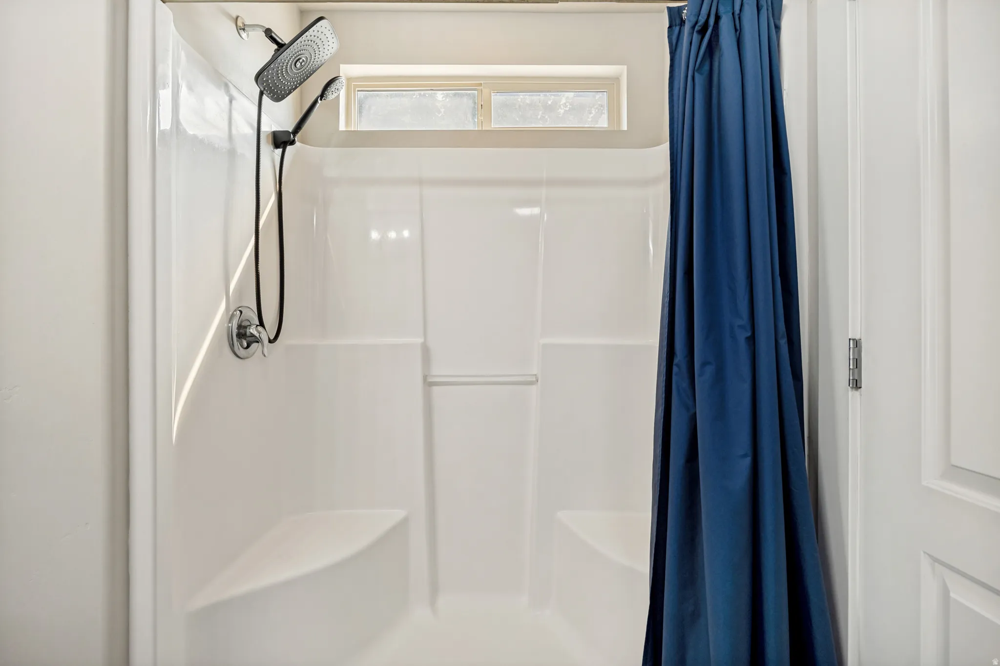 Shower enclosure featuring a multi-function showerhead with a handheld attachment, an integrated window, and two built-in seating areas
