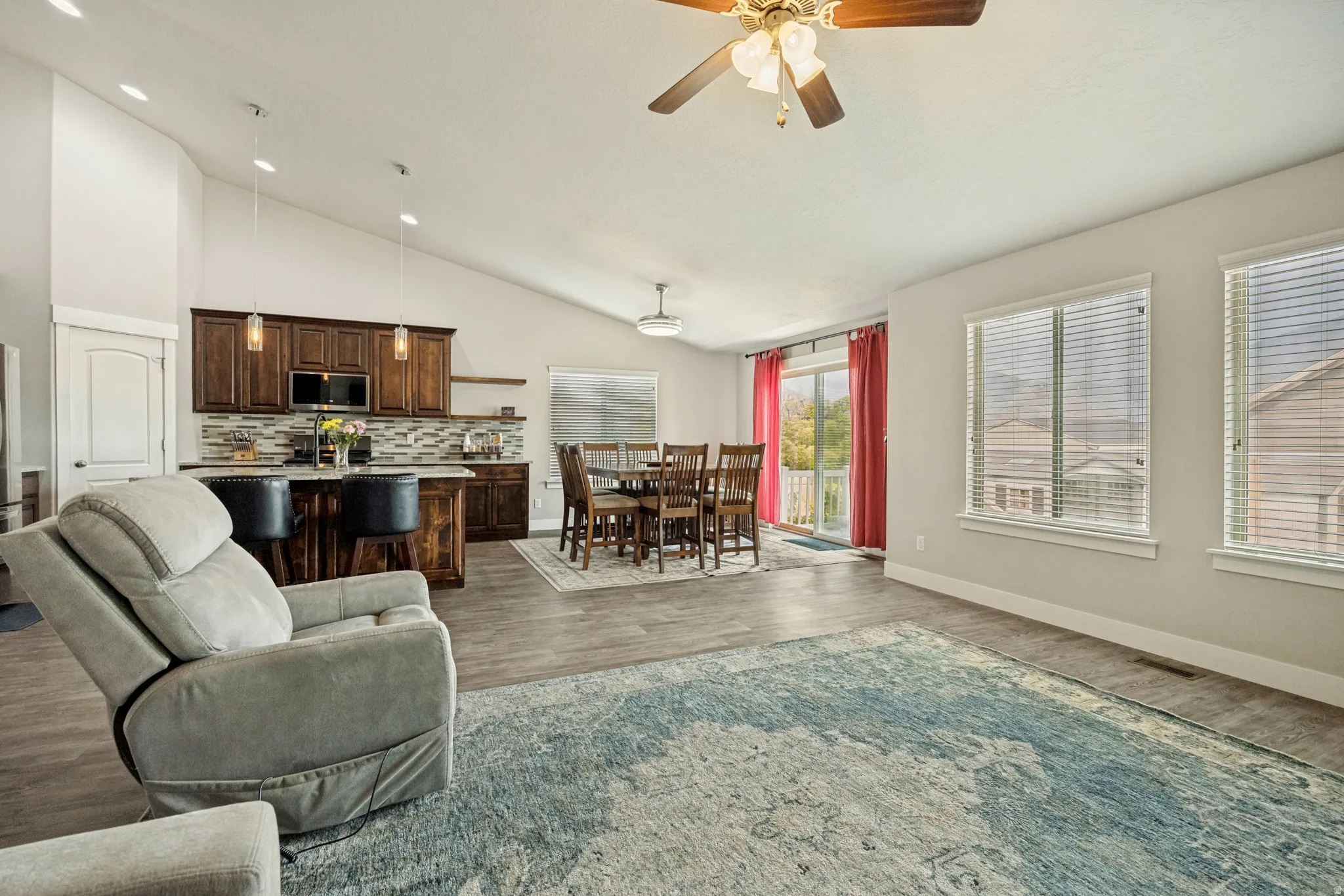 Vaulted ceilings extend over the open-concept living area featuring wood-finish flooring