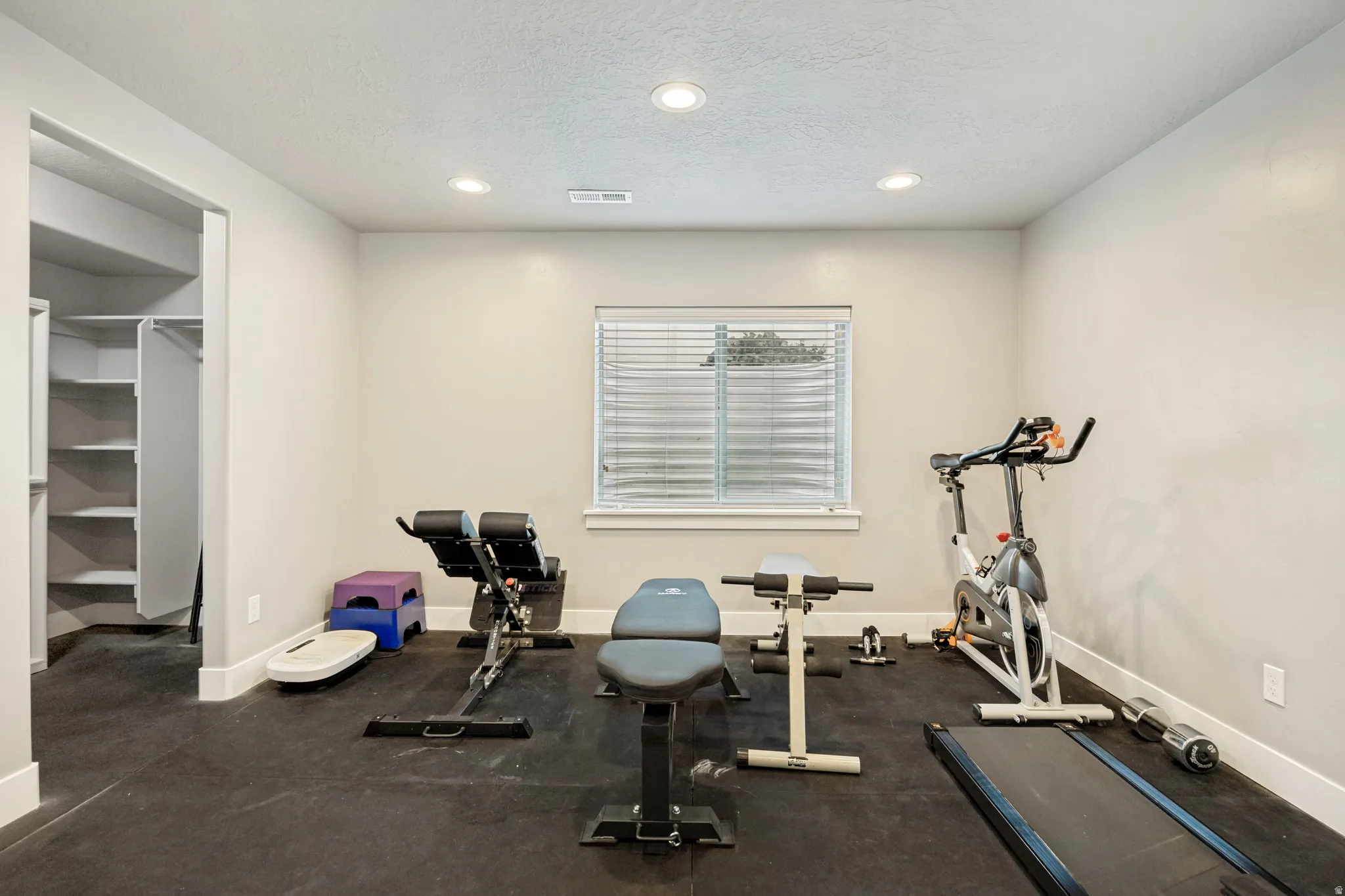 Spacious room featuring neutral painted walls, recessed lighting, and a window with horizontal blinds