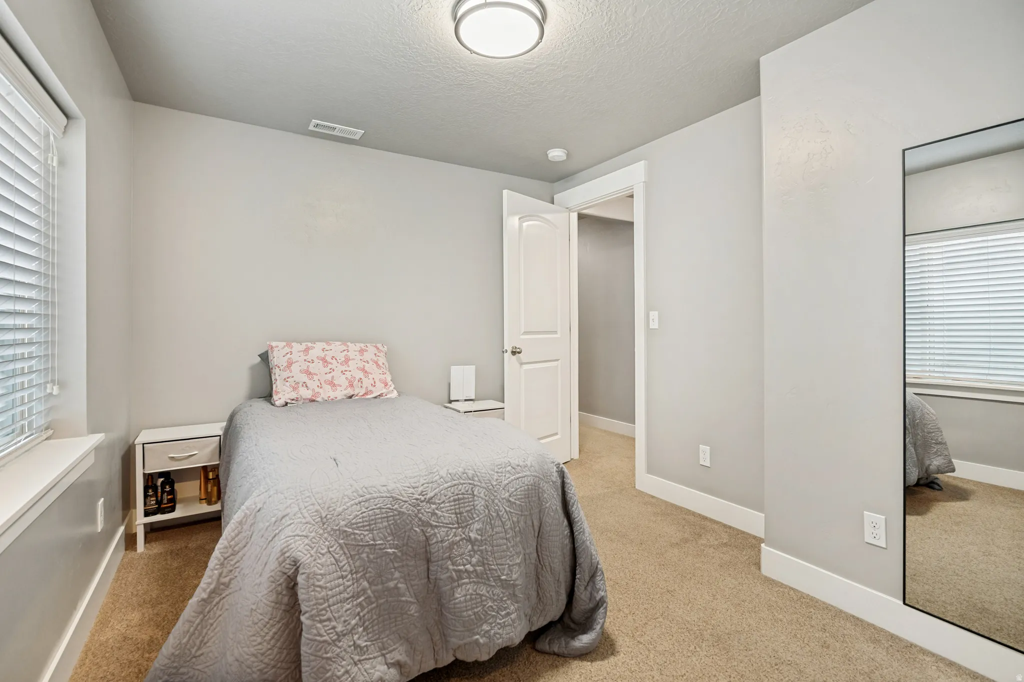 Carpeted room featuring a window with blinds, light gray walls, white trim, and an overhead flush mount light fixture