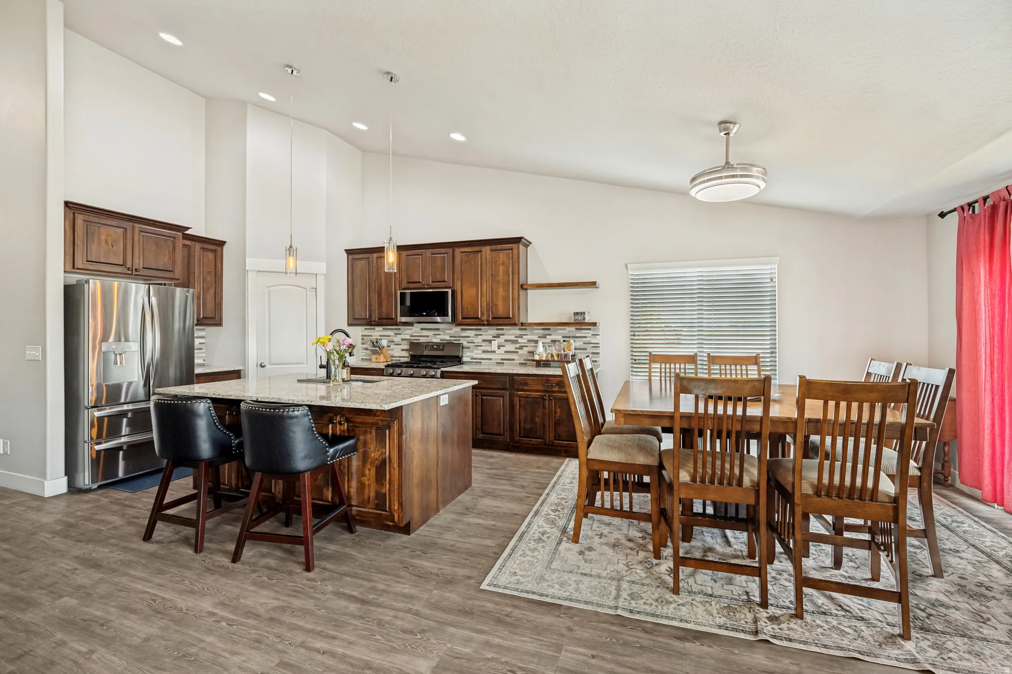 Spacious kitchen featuring rich wood cabinetry, stainless steel appliances, a large island with a light-toned countertop, and wood-finish flooring