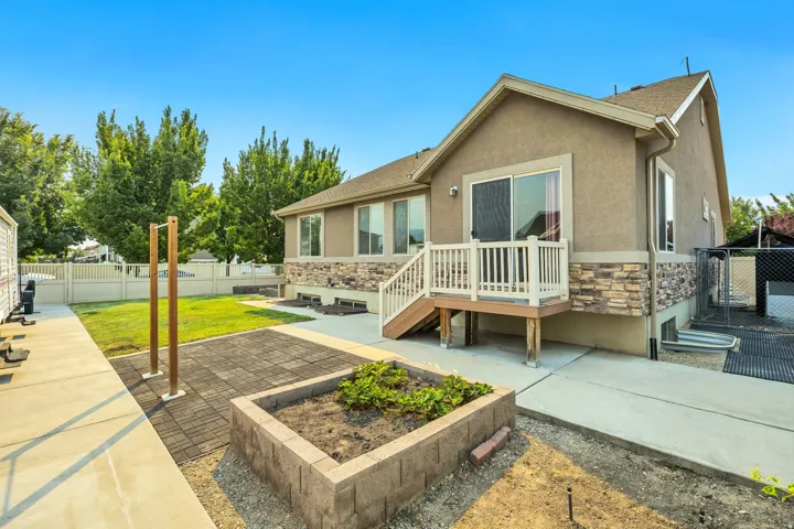 Rear exterior featuring a multi-level deck with white railings, stone veneer accents, stucco siding, and a sliding glass door