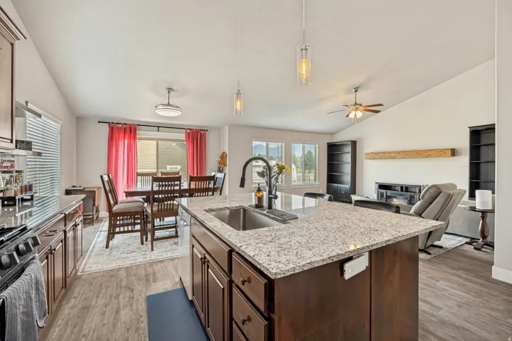 Kitchen island featuring a granite countertop, undermount sink, and dark wood cabinetry