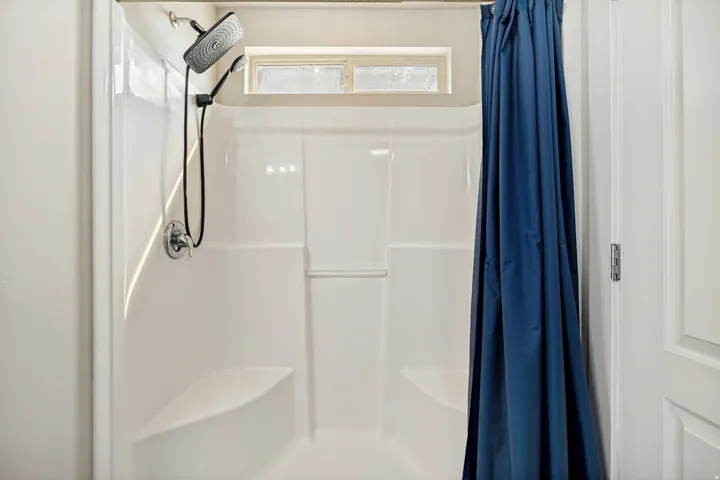 Shower enclosure featuring a multi-function showerhead with a handheld attachment, an integrated window, and two built-in seating areas