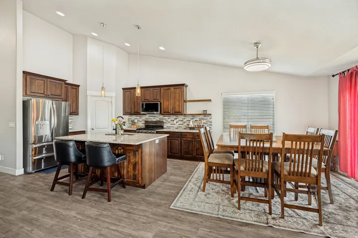 Spacious kitchen featuring rich wood cabinetry, stainless steel appliances, a large island with a light-toned countertop, and wood-finish flooring