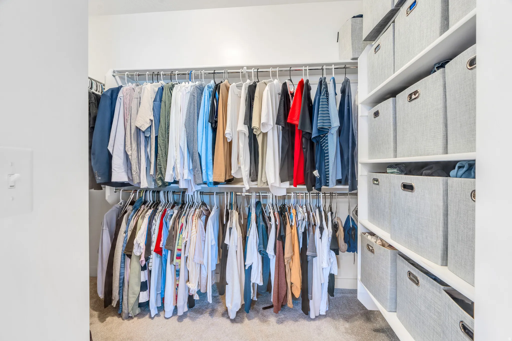 Custom closet system featuring dual-level hanging rods, built-in shelving, and light-toned carpet flooring