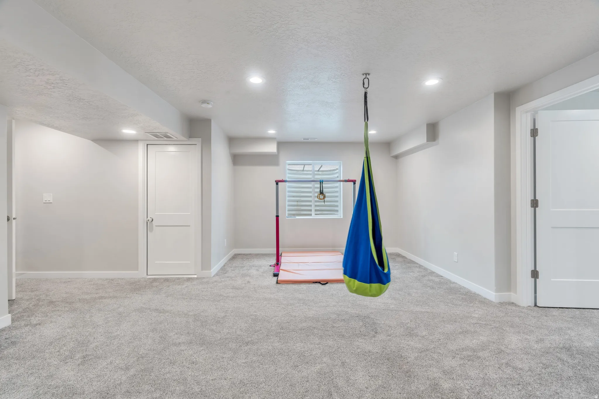 Spacious carpeted room featuring recessed lighting, white trim, and a window with white shutters