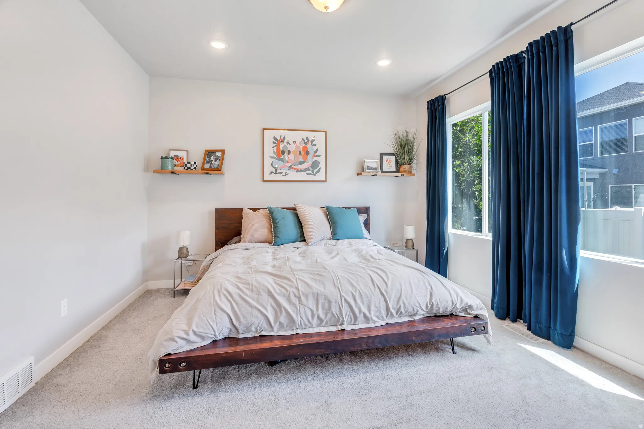 Bright room featuring light gray carpeting, recessed ceiling lighting, and large windows with privacy drapery