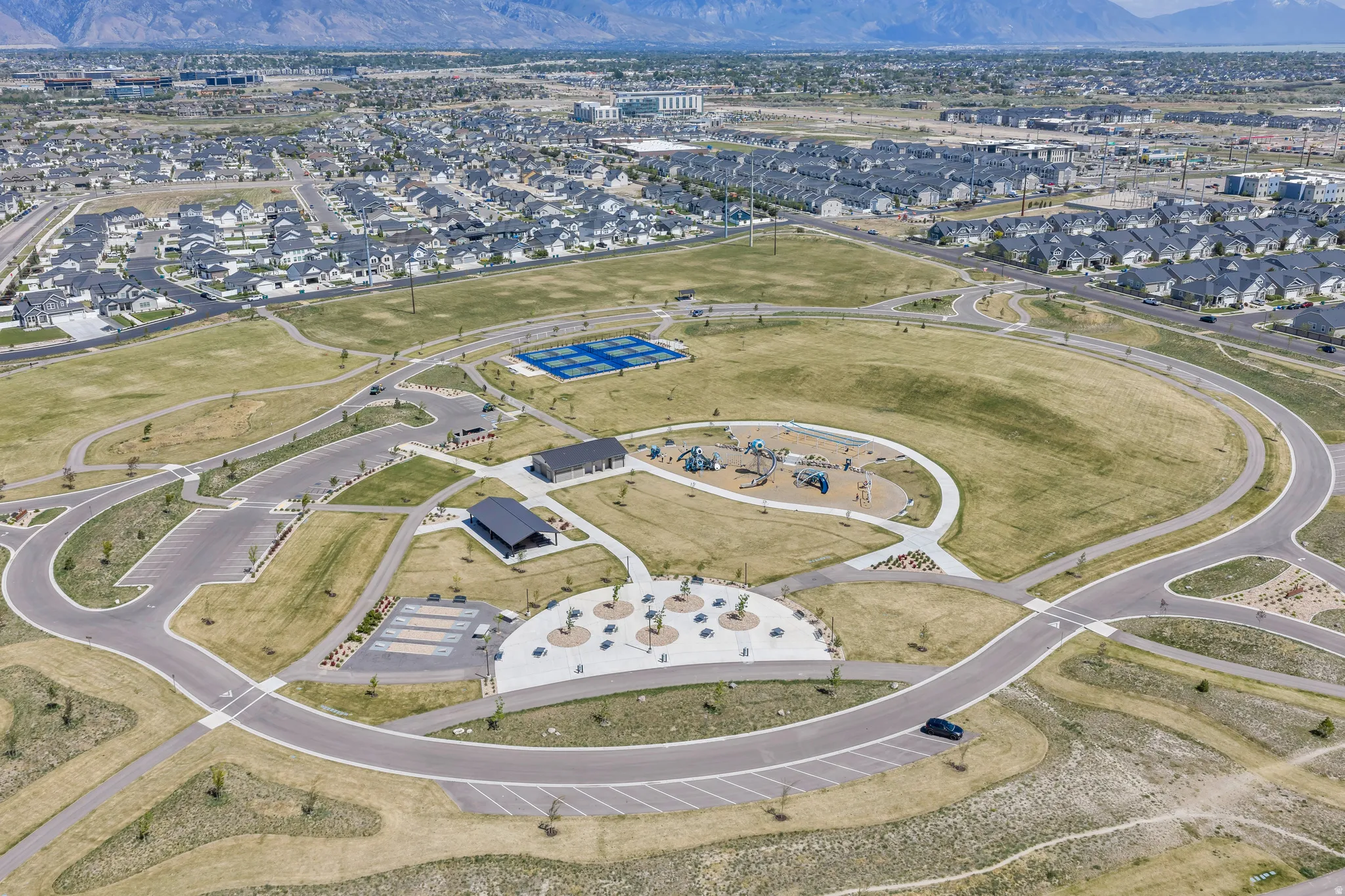 Expansive community park featuring multiple recreational areas, including tennis courts, a playground, and bocce ball courts