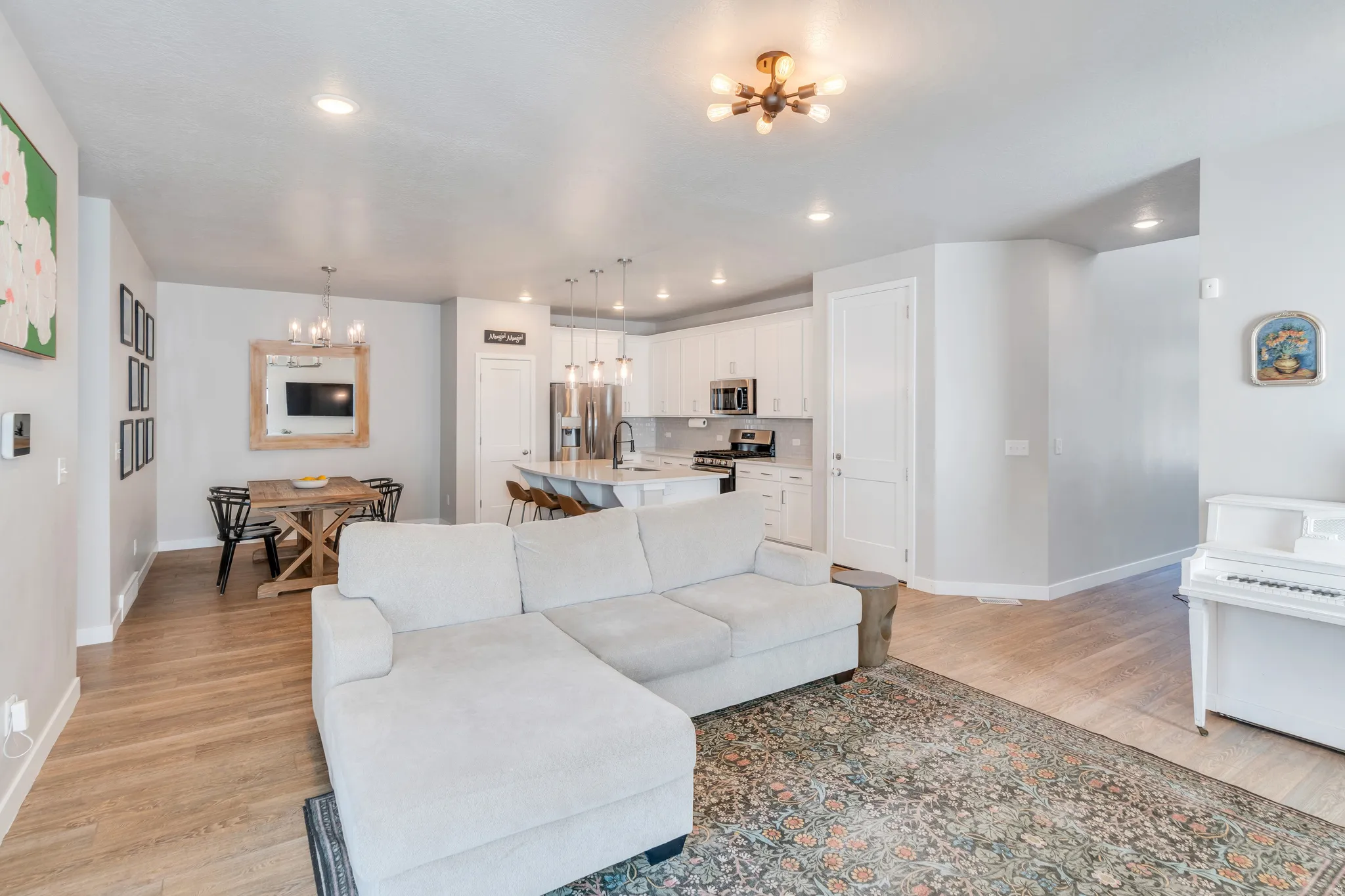 Open-concept living space featuring wood-finish flooring throughout, a modern chandelier, and recessed lighting